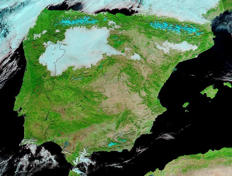 Imagen en falso color del MODIS donde se realzan las zonas nevadas: la nieve en color cian intenso. Nubes en las gamas de blanco, con sus topes formados mayoritariamente por gotitas de agua, hasta el azulado-cian con topes fríos y conformadas por cristalitos de hielo. La nieve está cubriendo exclusivamente las zonas más altas de montaña: Pirineos, Cordillera Cantábrica, Ibérico, Sistema Central y Sierra Nevada. Estamos en el día 24, antes de las nevadas generalizadas en el norte. Imagen NASA.