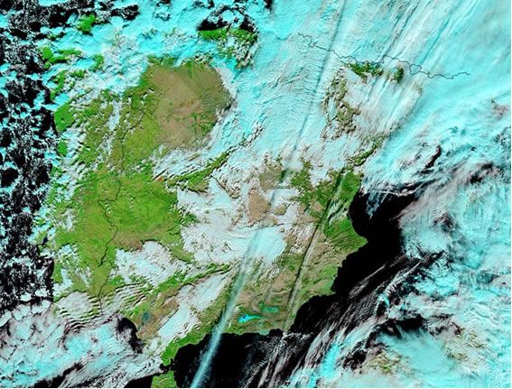 Imagen del MODIS en falso color del 25 de diciembre durante el mediodía donde la nieve y nubes, cuyos topes están formados por cristalitos de hielo, están realzadas en cian. Se están produciendo las primeras nevadas. Imagen de la NASA.