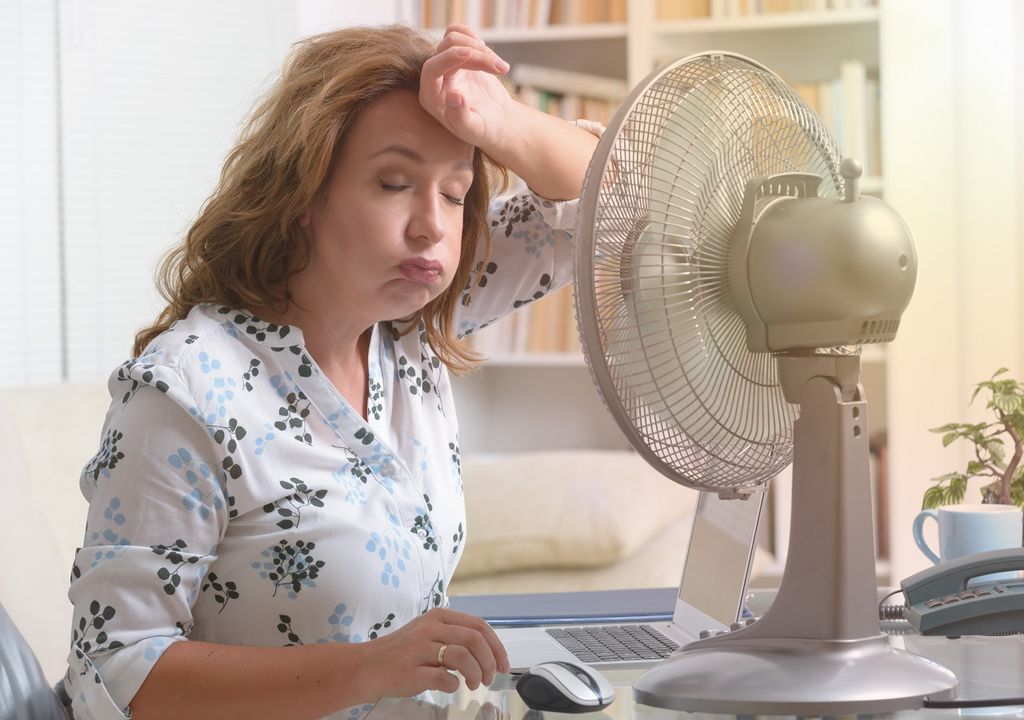 Mujer en su escritorio con ventilador