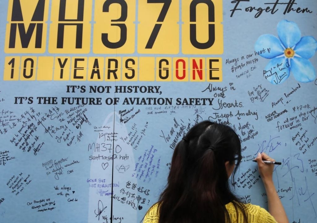 Une femme écrit un message sur un panneau lors d'un événement pour commémorer les 10 ans de la disparition du vol MH370 de Malaysia Airlines, dans un centre commercial à Subang Jaya, dans la banlieue de Kuala Lumpur, en Malaisie, le dimanche 3 mars 2024. Crédit : AP Photo/FL Wong