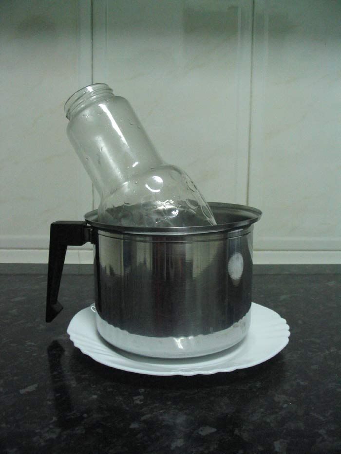 Botella o recipiente base de cristal transparente y recipiente-1, en este caso de metal con agua caliente en su interior. Botella o recipiente base de cristal transparente y recipiente-1, en este caso de metal con agua caliente en su interior.