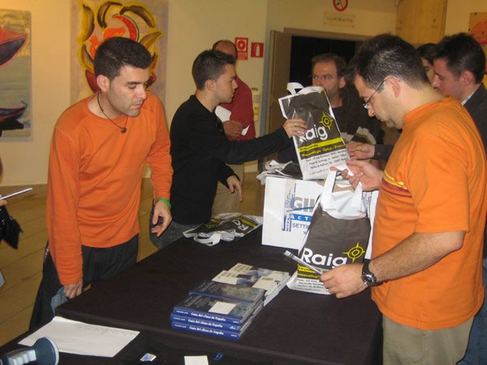 Emilio y Pedro reparten en la mesa de RAIG bolsas, artículos y camisetas de regalo. Libros de José Miguel Viñas y Vicente Aupí se vendieron en dicha mesa.
