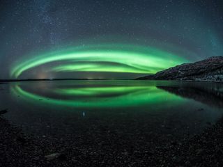 Aurora arqueada y cielo estrellado