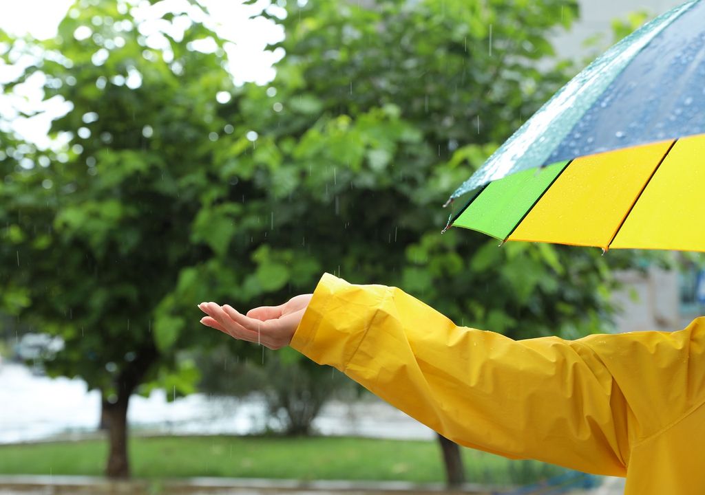 Mano femenina estirada hacia la lluvia Mano femenina estirada hacia la lluvia