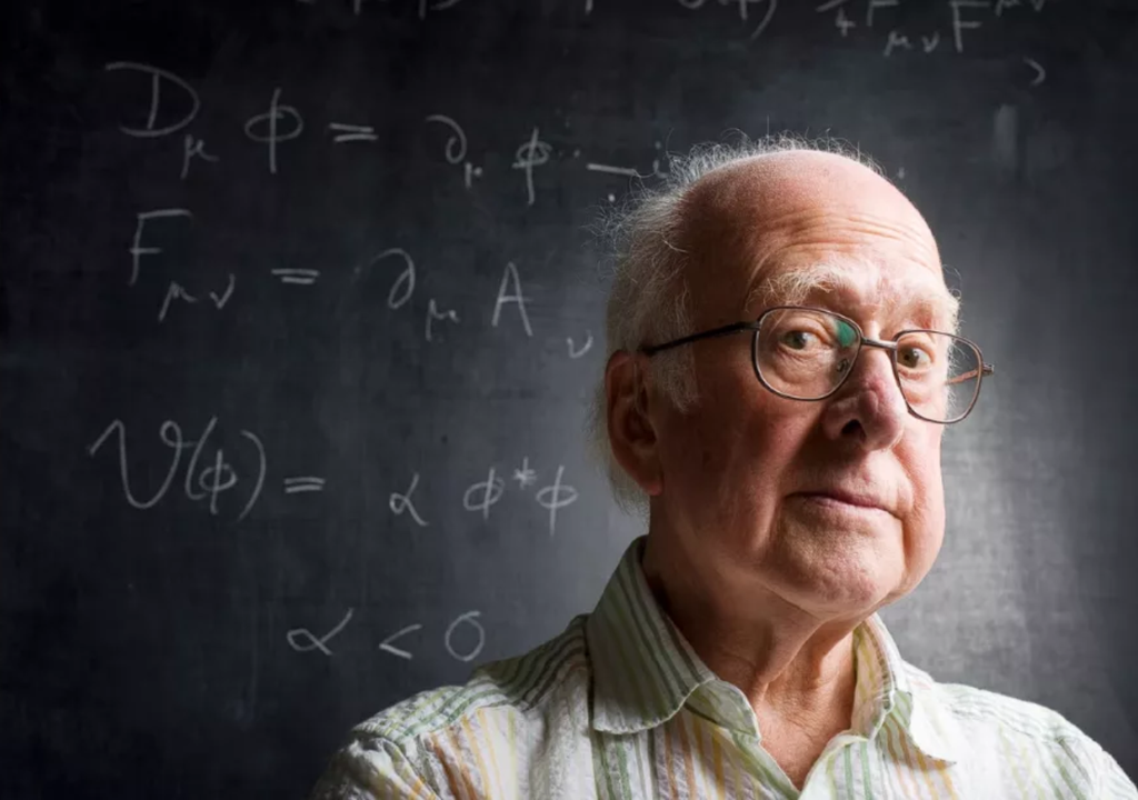 Peter Higgs delante de una pizarra negra con fórmulas físicas escritas con tiza blanca