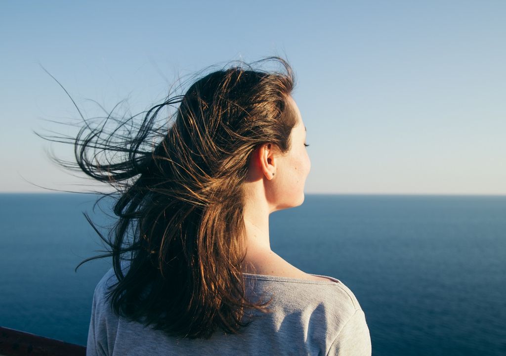 Mujer frente al mar; cabello movido por el viento