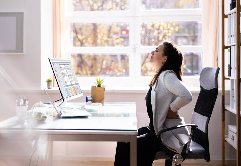 persona sentada frente al computador con malestar en la espalda