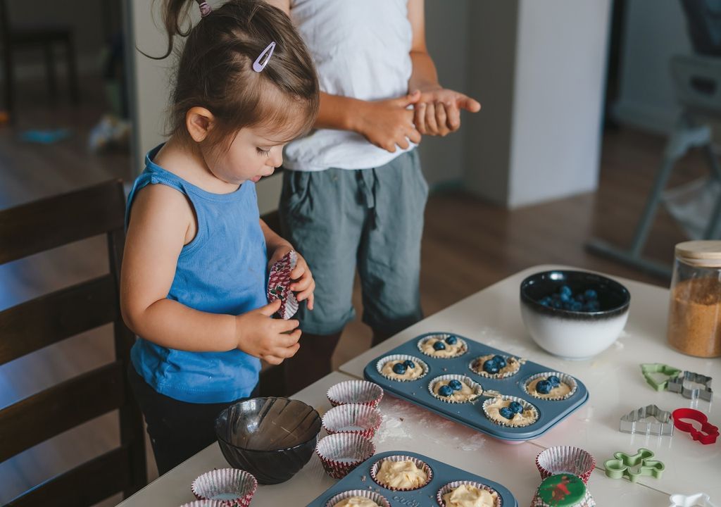 Bambina che cucina cupcakes con mirtilli