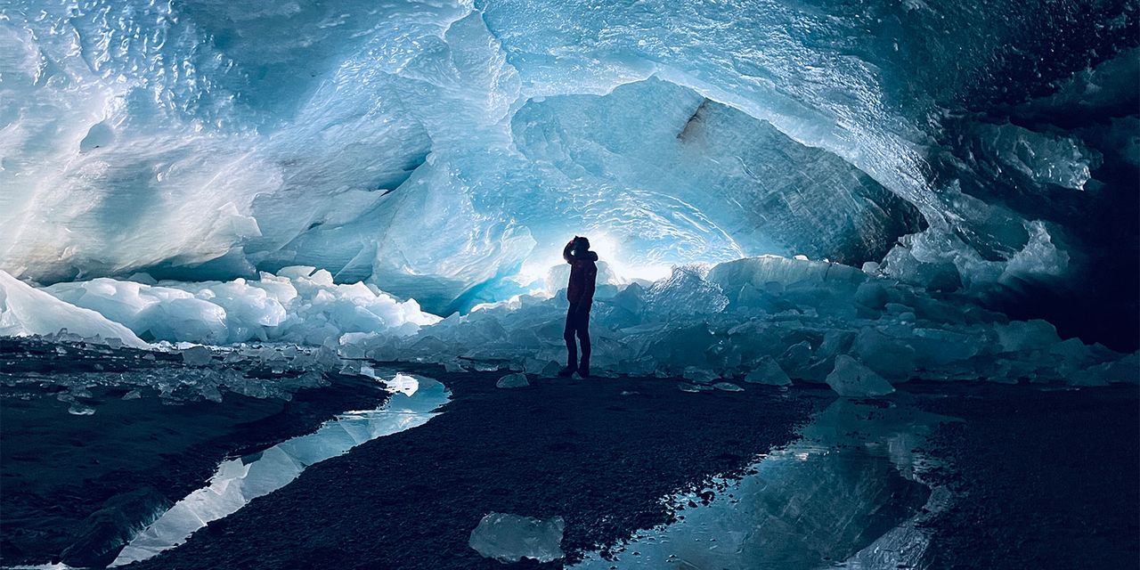 Una persona está parada en una cueva de hielo dentro de un glaciar. Dentro del glaciar Morteratsch, en Suiza, se encuentra una gran cueva de hielo: una señal impresionante y a la vez alarmante del retroceso glaciar continuo y acelerado, que se refleja en la disminución del número de glaciares en los Alpes y en todo el mundo. (Imagen: Lander Van Tricht / ETH Zurich, Cátedra de Glaciología).
