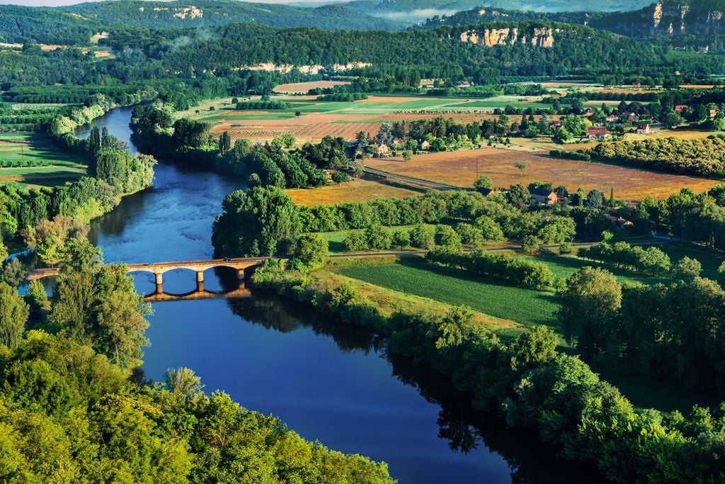 Wälder und Wasser: Eine mittelalterliche Brücke verbindet die Ufer der Dordogne. Foto: Adobe Stock