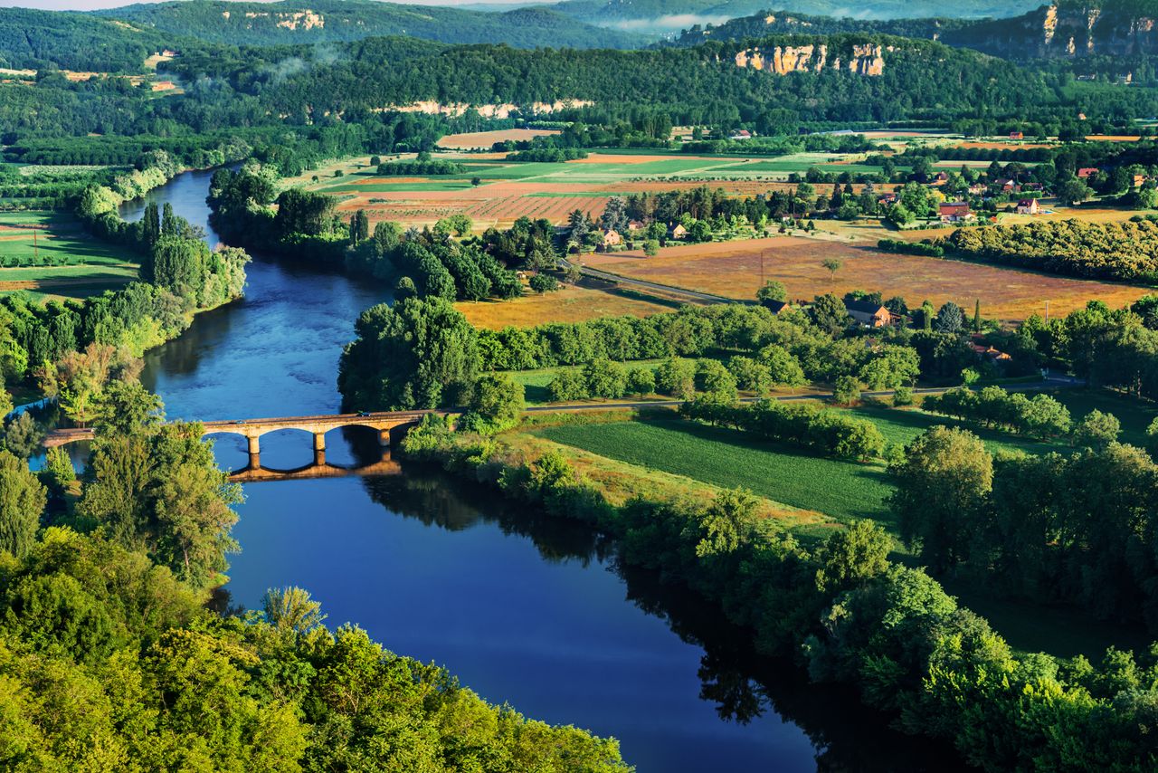 Wälder und Wasser: Eine mittelalterliche Brücke verbindet die Ufer der Dordogne. Foto: Adobe Stock