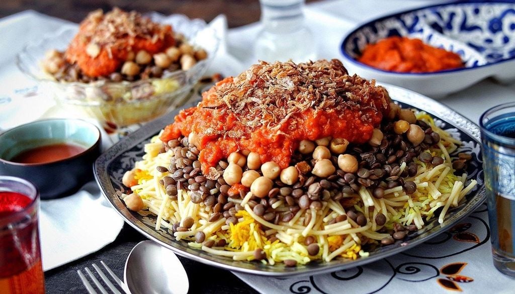 Koshari Koshari, el plato tradicional egipcio que combina arroz, lentejas, pasta, garbanzos y salsa de tomate especiada.