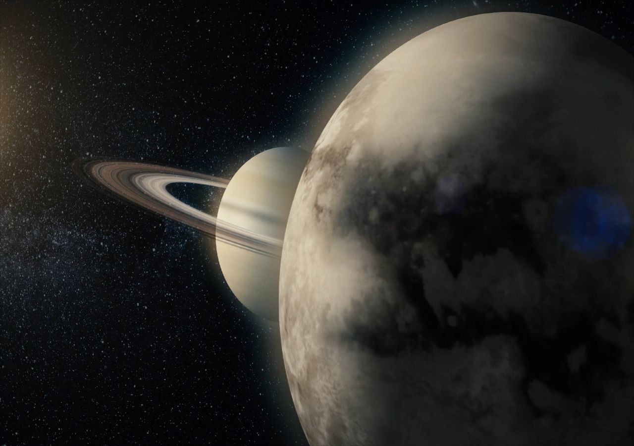 Vista de Titã, em primeiro plano, a maior Lua do planeta Saturno, com os seus anéis, em segundo plano.