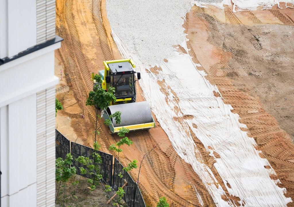 Vista aérea de una obra en la que una aplanadora compacta capas de tierra y grava sobre geotextil.