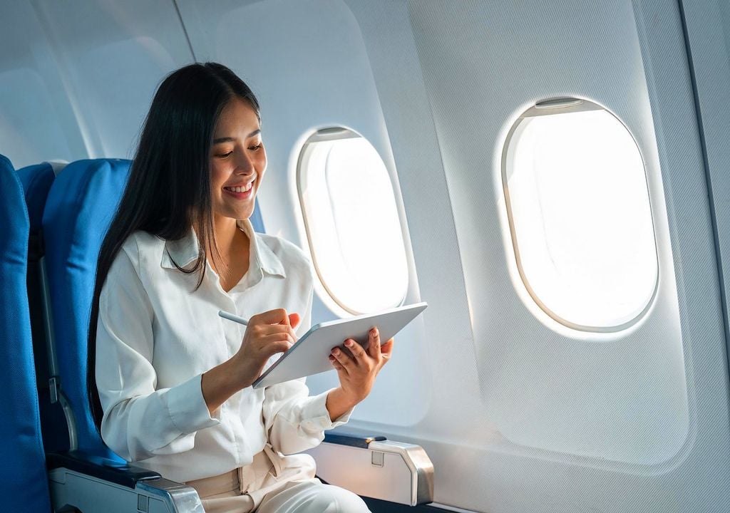 Mujer con una tablet en un avión Mujer con una tablet en un avión
