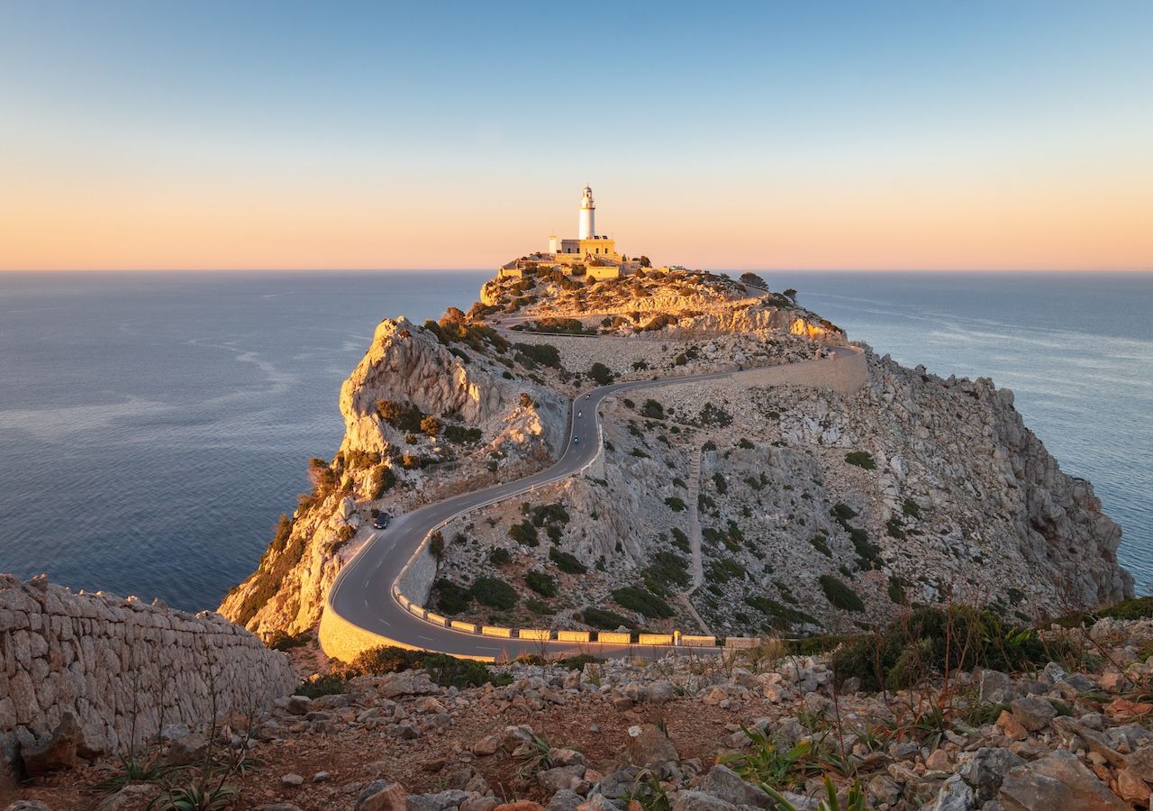 El faro blanco de Formentor y, en los días despejados, la silueta de Menorca en el horizonte, crean el escenario perfecto para capturar una puesta de sol inolvidable.