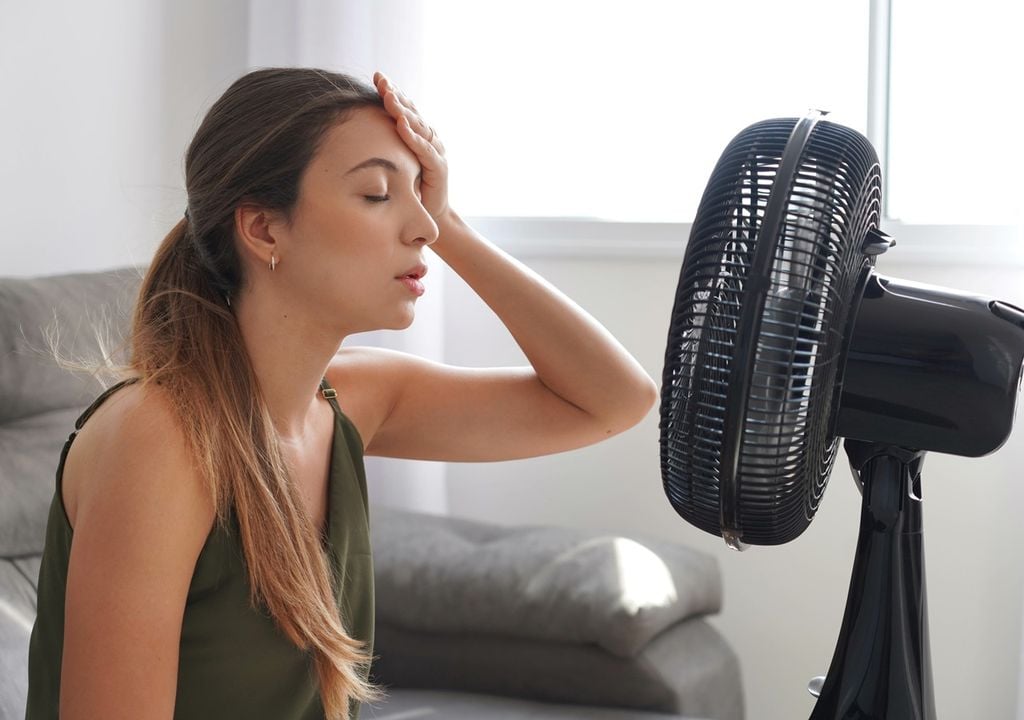 persona sintiendo calor frente a un ventilador para refrescarse