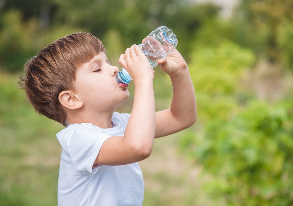 niño bebiendo agua de una botella plástica niño bebiendo agua de una botella plástica