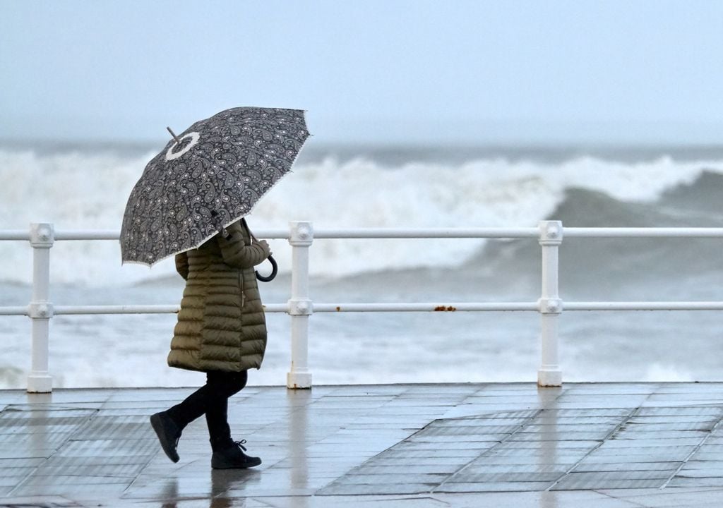 Persona caminando bajo la lluvia; marejadas