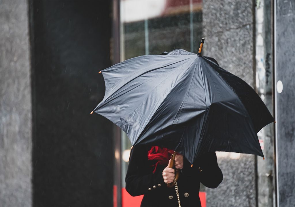 persona llevando un paraguas contra el viento