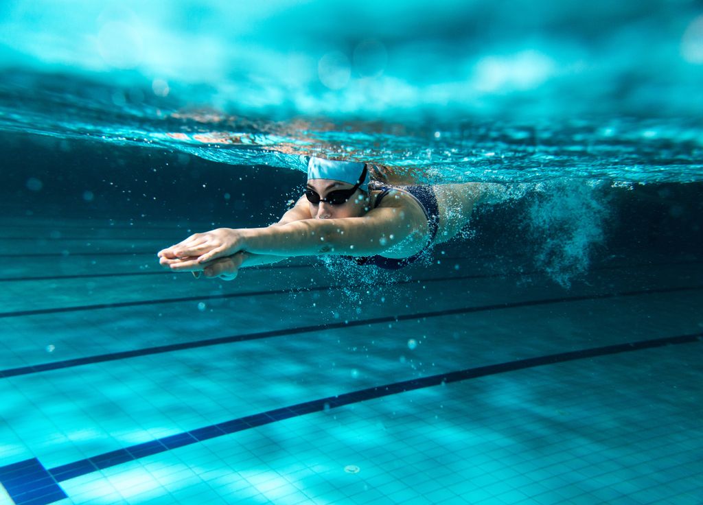 persona nadando bajo en el agua en una piscina