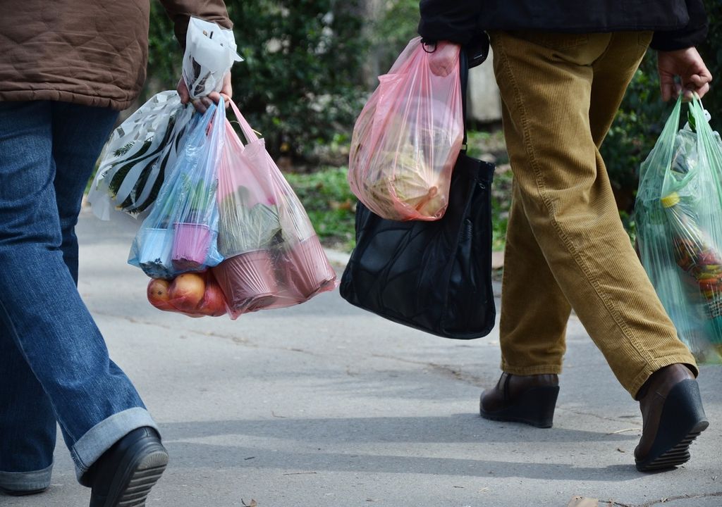 personas llevan sus compras en bolsas plásticas personas llevan sus compras en bolsas plásticas