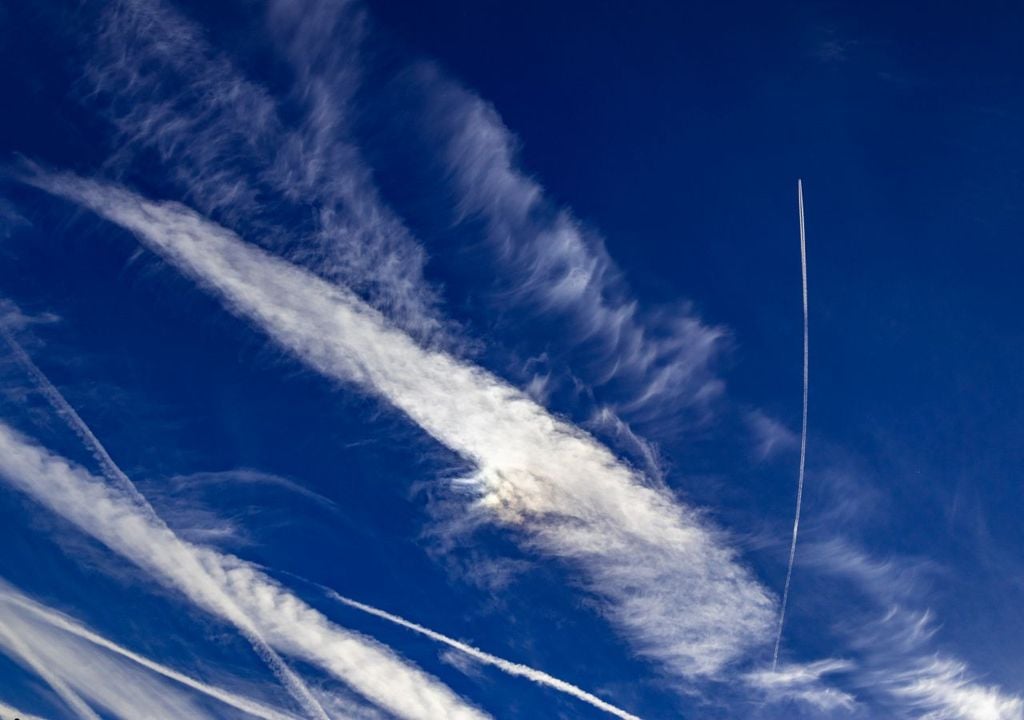 Das Foto zeigt hohe Wolkenfelder und Kondensstreifen von Flugzeugen. Verschwörungstheoretiker sehen in Kondensstreifen etwas ganz anderes: Total verrückt!