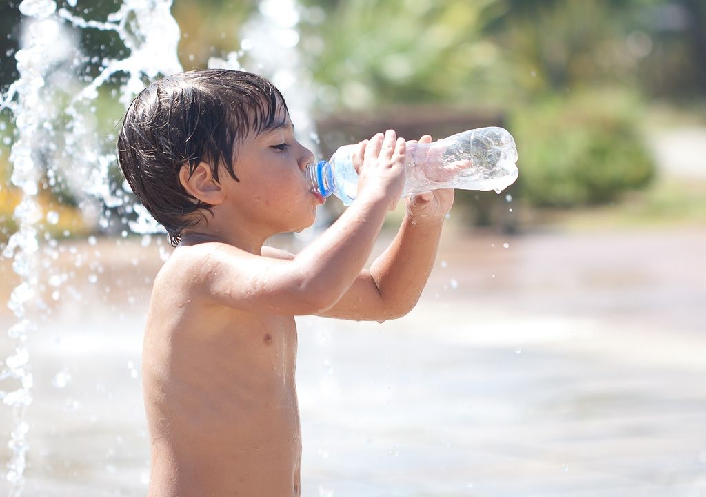 Niño tomando agua por calor extremo