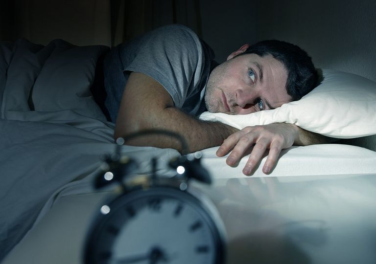 Hombre acostado en la cama sin poder dormir Hombre acostado en la cama sin poder dormir