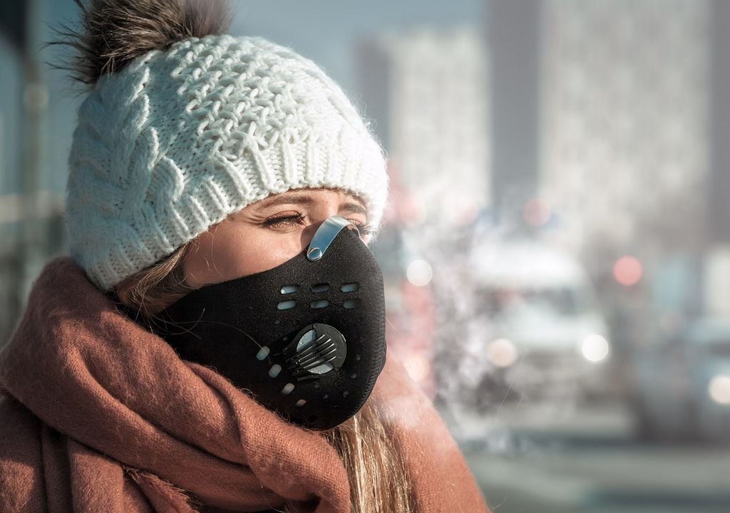 Mujer protegiéndose con mascarilla de la contaminación del aire