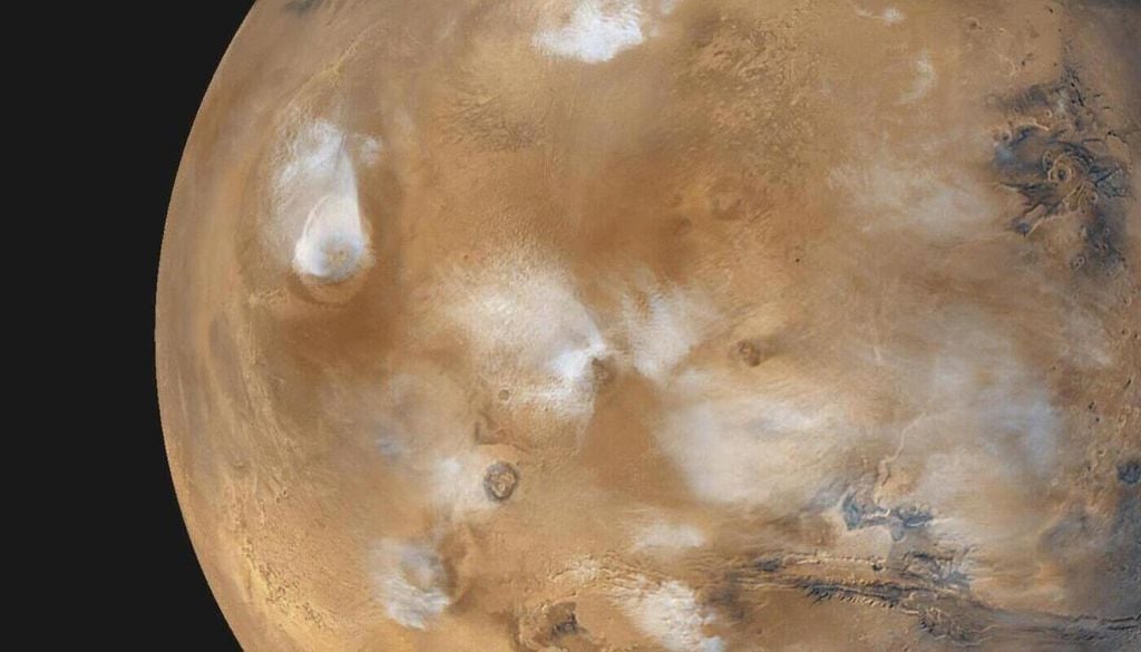 Globalaufnahme vom Mars aus dem April 1999, vom NASA-Satelliten Mars Global Surveyor. Hier hängen gerade bläulich-weiße Wassereiswolken über den Tharsis-Vulkanen. Globalaufnahme vom Mars aus dem April 1999, vom NASA-Satelliten Mars Global Surveyor. Hier hängen gerade bläulich-weiße Wassereiswolken über den Tharsis-Vulkanen. Bild: NASA/JPL/MSSS