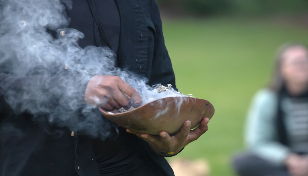 Prato cerimonial de madeira com galhos defumados, o ritual de boas-vindas em um evento comunitário indígena na Austrália.
