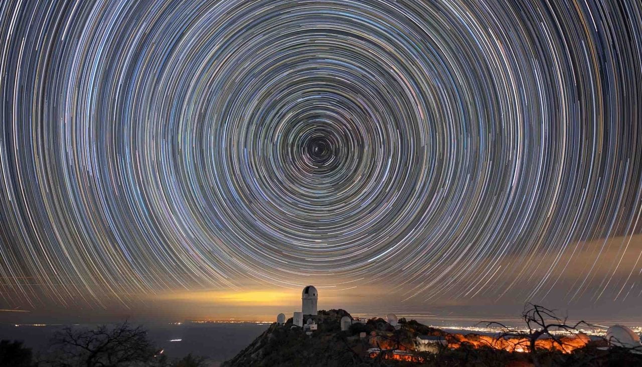 Rastros de estrelas sobrepostos ao telescópio Mayall, no Arizona, que alberga o Instrumento Espectroscópico de Energia Escura. Crédito: fotografia de Luke Tyas/Berkeley Lab e KPNO/NOIRLab/NSF/AURA