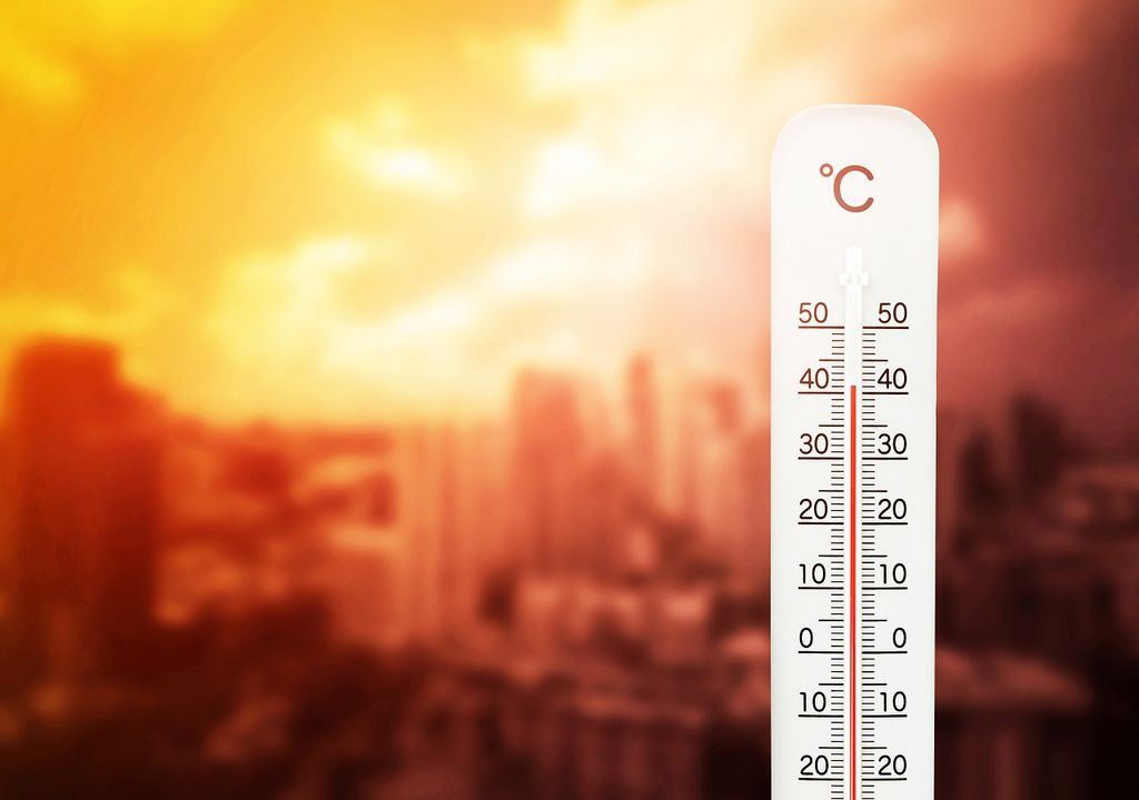 termómetro marcando casi 40 grados con el cielo y una ciudad de fondo en tonos anaranjados