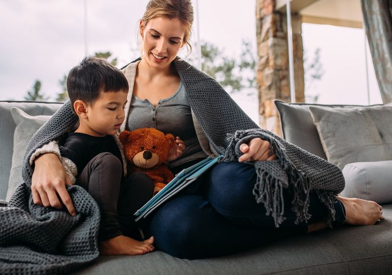 Madre e hijo sentados bajo una manta leyendo Madre e hijo sentados bajo una manta leyendo
