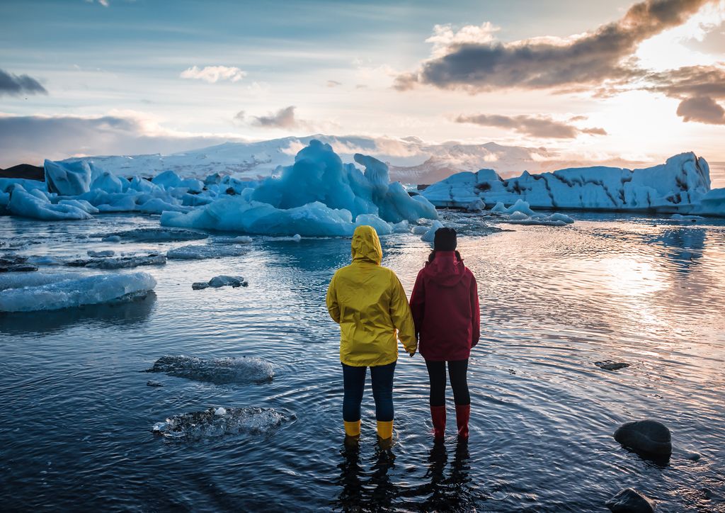 Two people watching on floating icebergs in Jokulsarlon glacier lagoon.