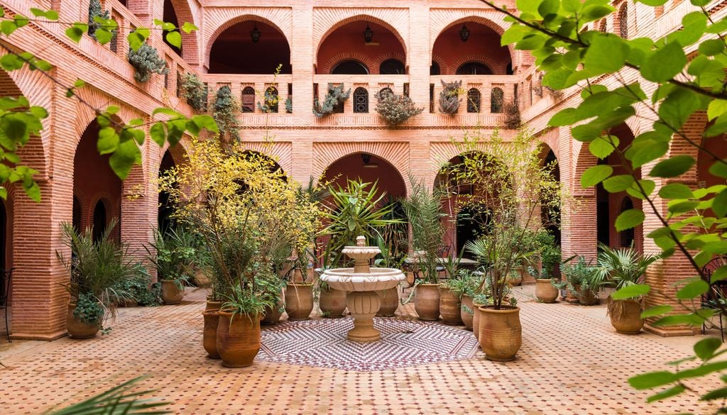 Jardin fleuri, arches et ornements en terre cuite à l'intérieur d'un riad à Marrakech. Jardin fleuri, arches et ornements en terre cuite à l'intérieur d'un riad à Marrakech.