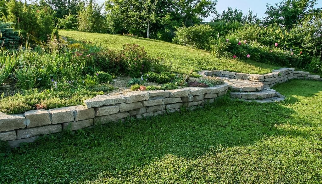 La combinación de piedra y vegetación estabiliza el suelo y suma textura al diseño.