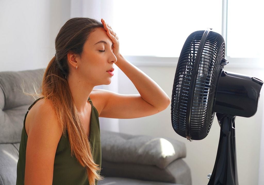 Mujer aliviándose del calor con un ventilador