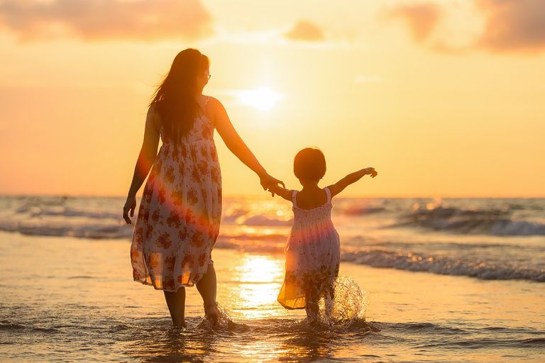 Madre e hija paseando por la playa durante el atardecer Madre e hija paseando por la playa durante el atardecer