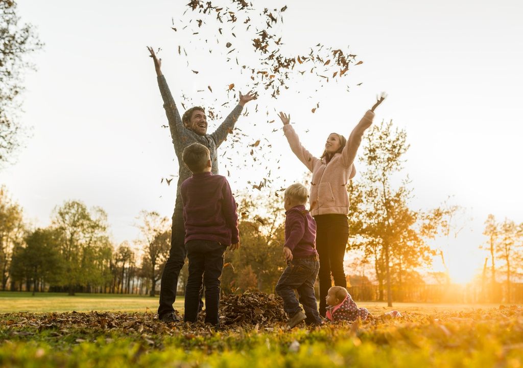 familia lanzando hojas secas al aire en una tarde otoñal