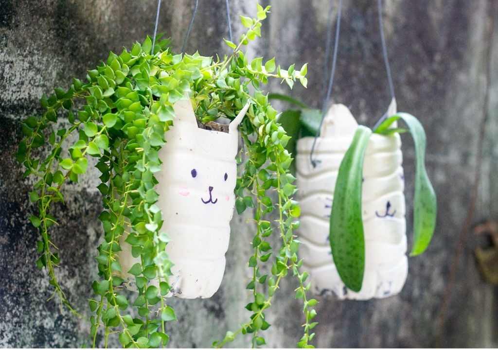 Garrafas de plástico pintadas usadas como vasos suspensos para plantas Garrafas de plástico pintadas usadas como vasos suspensos para plantas