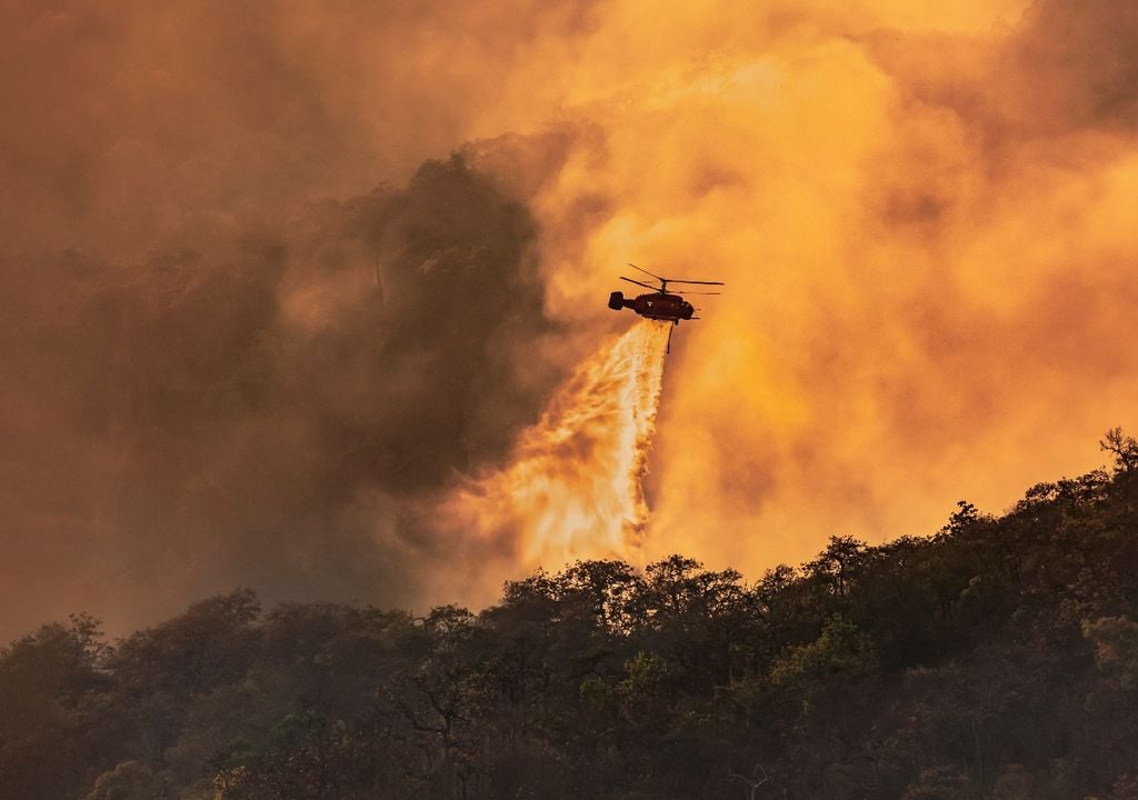 Helicóptero combatiendo incendio forestal, fondo humo