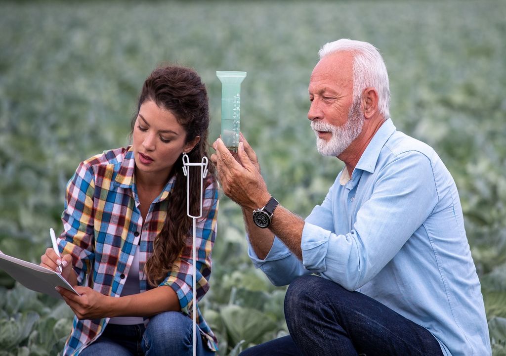 Hombre mayor y mujer joven registrando información de pluviómetro