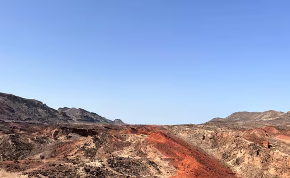 Capas de roca en diferentes tonalidades de rojo y marrón, bajo un cielo azul brillante. Estratos fósiles del Mioceno tardío de Lothagam en Turkana occidental. Foto de : Christian Rowan