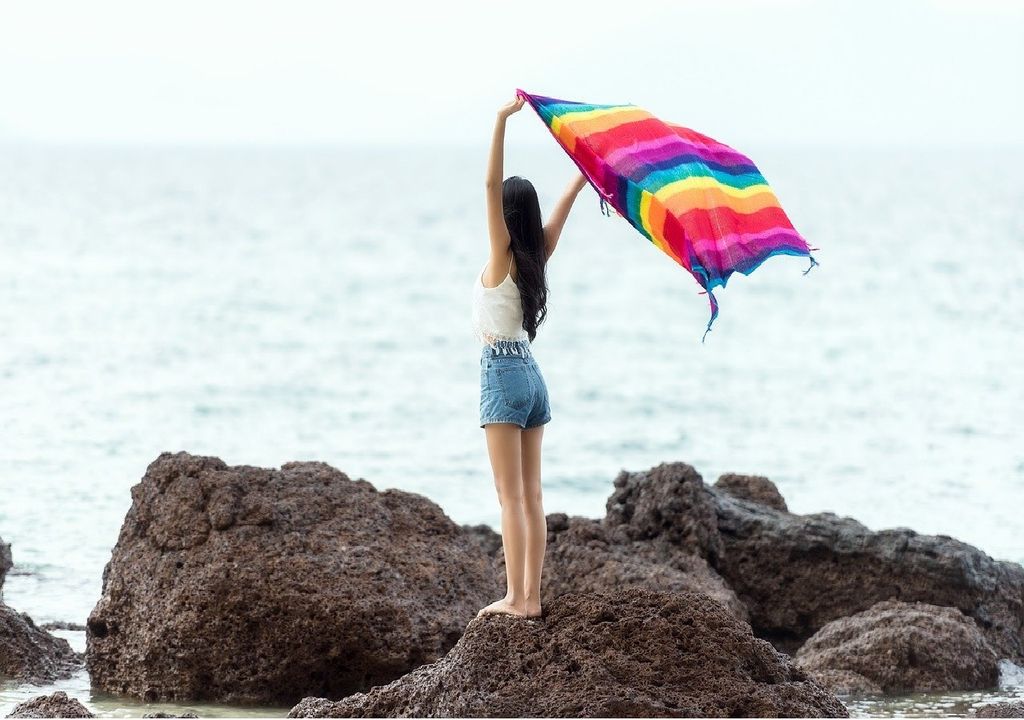 Mujer con pañuelo al viento en las rocas de una playa