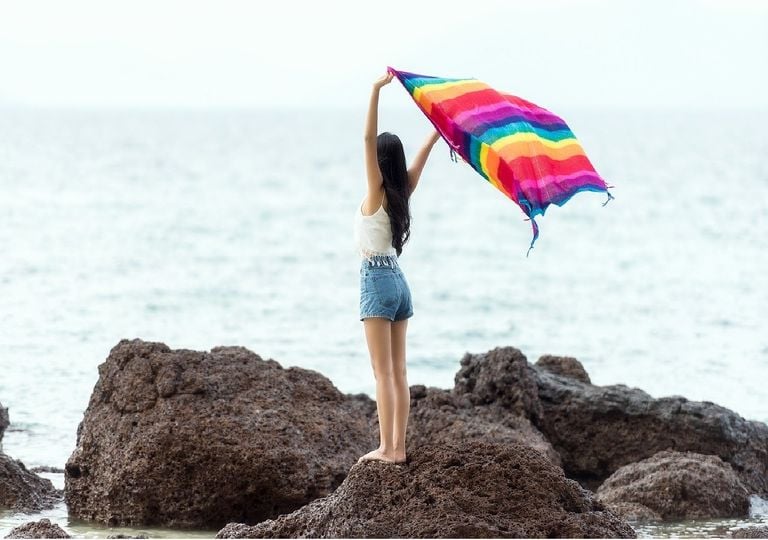 Mujer con pañuelo al viento en las rocas de una playa Mujer con pañuelo al viento en las rocas de una playa