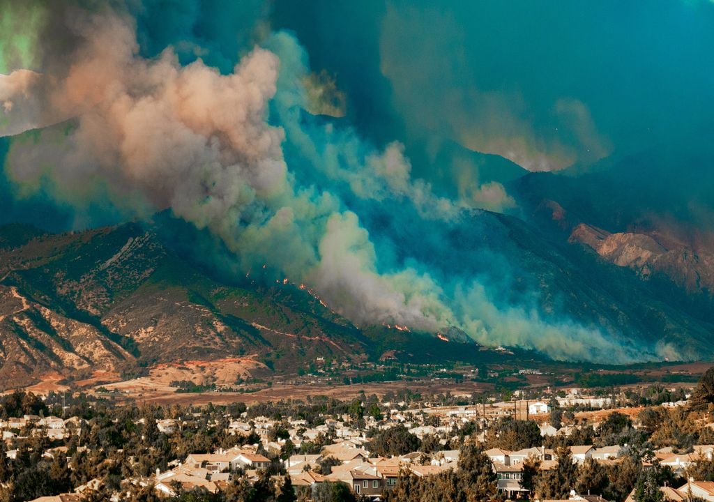 incendio forestal arrasando una ladera de montaña cerca de una área poblada