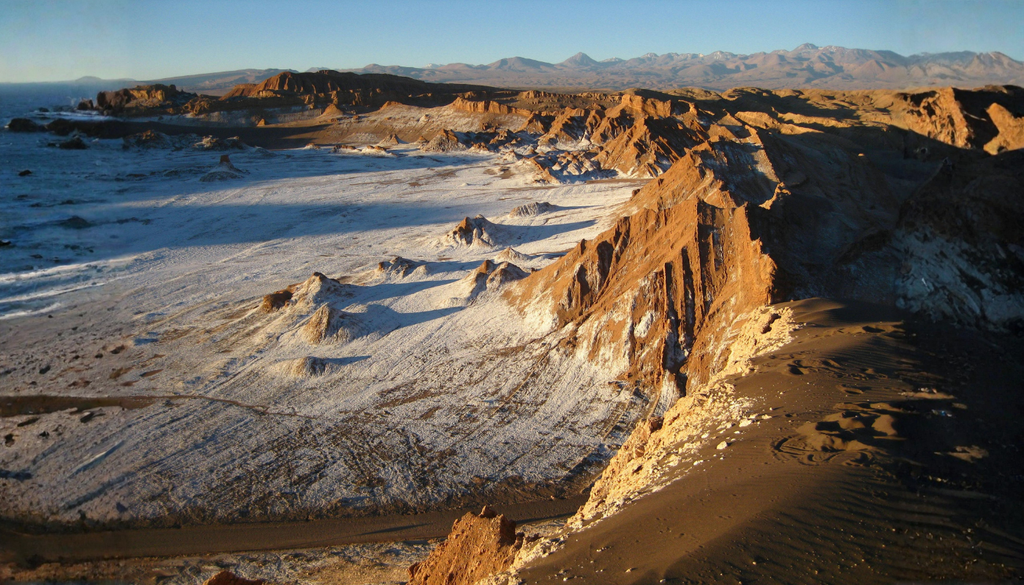 Valle de la Luna, interior de Atacama: costra salina, roca y gravilla bajo un cielo despejado. Sin agua ni vegetación que frenen el sol, el suelo responde como una plancha de día y, al anochecer, devuelve el calor al espacio sin manta de nubes.