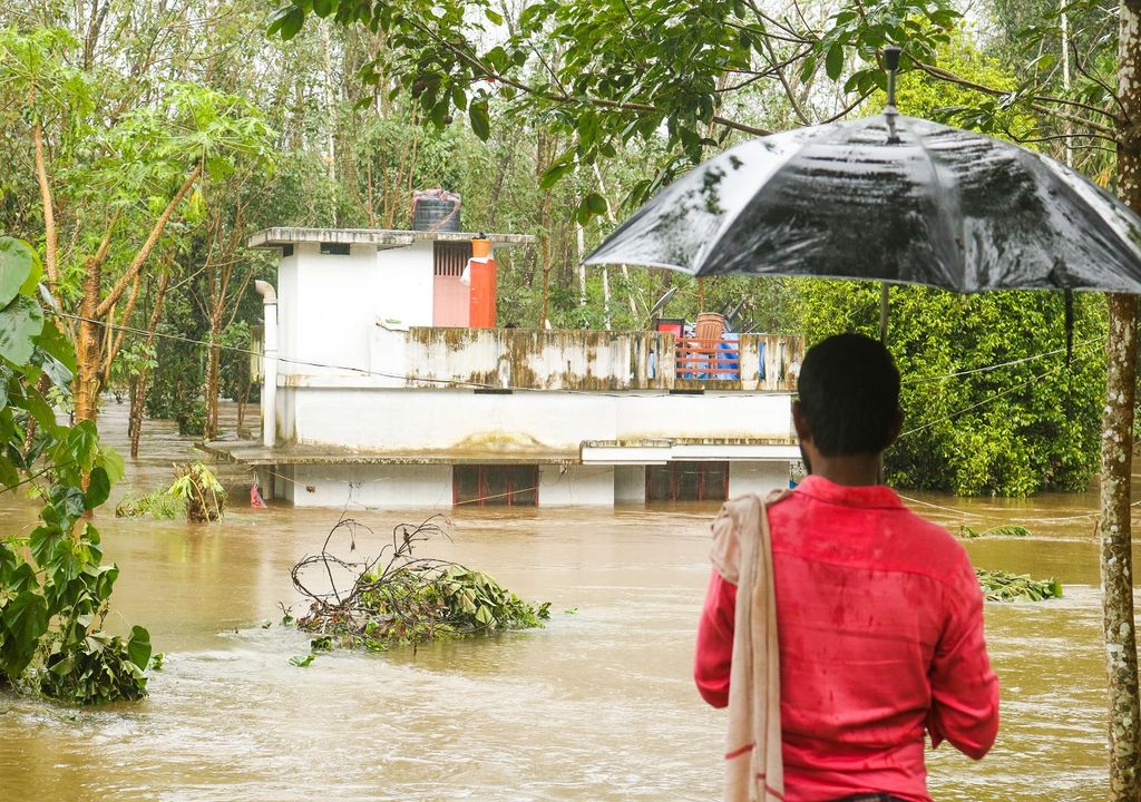 Persona con paraguas contemplando su casa inundada